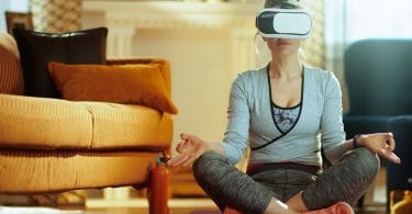 Mulher sentada em posição de meditação com óculos de realidade virtual