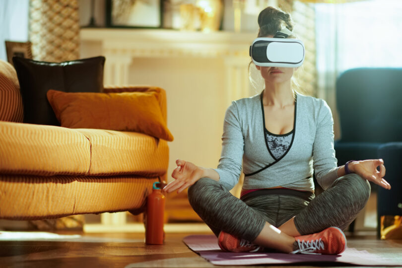 Mulher sentada em posição de meditação com óculos de realidade virtual