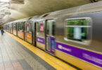 Estação de metrô em Nova York, com o trem passando em alta velocidade.