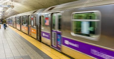 Estação de metrô em Nova York, com o trem passando em alta velocidade.