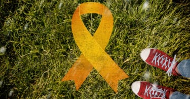 Símbolo do Setembro Amarelo sobre grama verde e um pé humano ao lado.