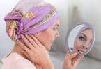 Mulher com bandana na cabeça se olhando no espelho de mão