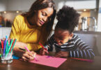 Mãe e filha desenhando em uma folha rosa.