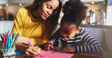 Mãe e filha desenhando em uma folha rosa.