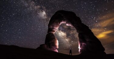 Pessoa em arco de pedra olhando céu