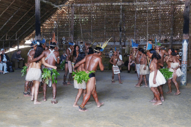 Indígenas realizando um ritual dentro de uma oca