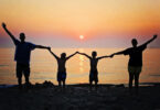 Família de mãos dadas na praia.