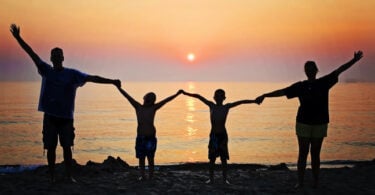 Família de mãos dadas na praia.