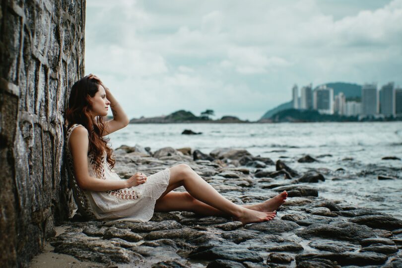 Mulher triste sentada em pedras