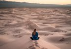 Mulher sentada de costas em deserto de areia