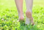 Pés descalços andando em gramado verde florido.