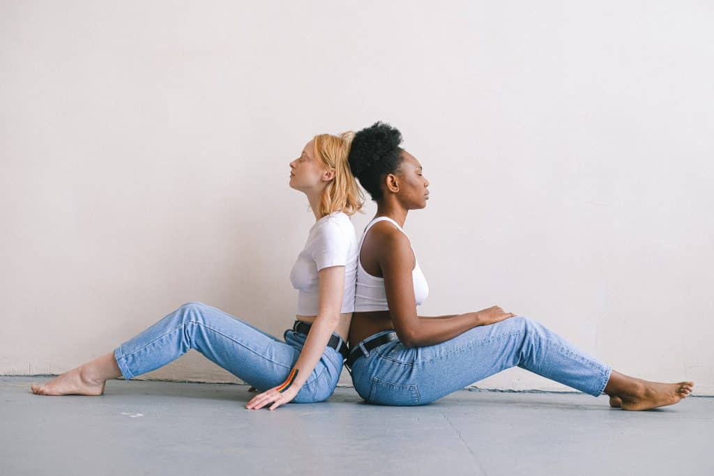 Duas mulheres sentadas no chão de costas uma para a outra