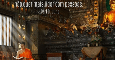 Solidão: monge vestindo uma túnica laranja sentado no chão de um templo budista enquanto lê um livro, com a frase "A solidão é perigosa e viciante. Quando você se dá conta da paz que existe nela, não quer mais lidar com pessoas" de Carl G Jung escrita em branco na parte superior esquerda da imagem.
