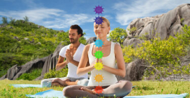 casal meditando na posição de lótus com sete símbolos de chakra sobre fundo de natureza