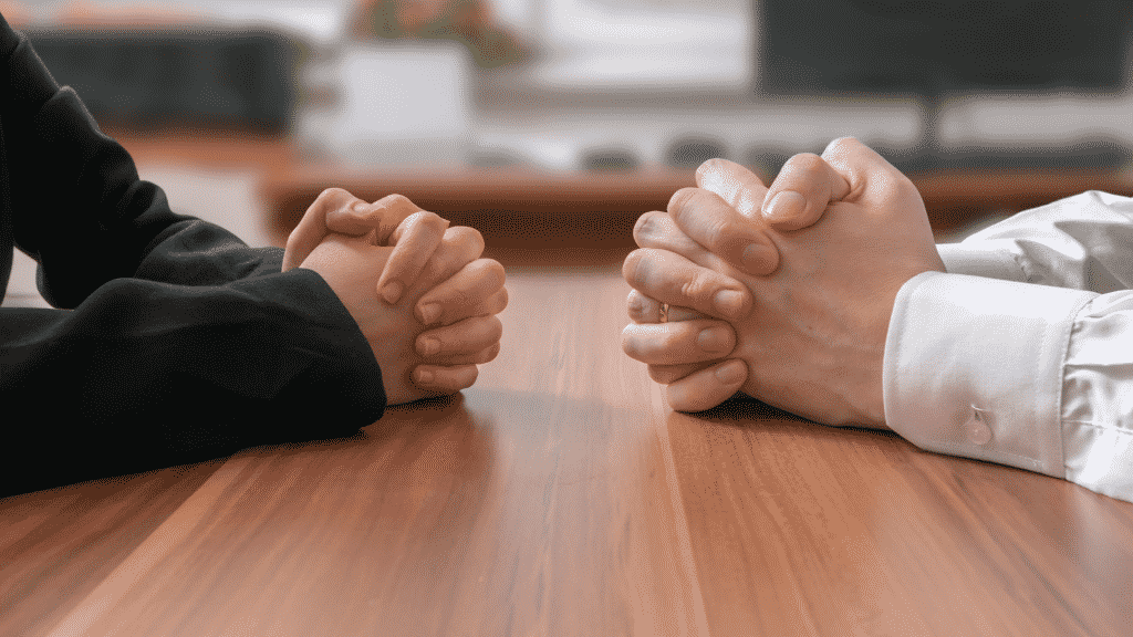 duas pessoas com as mãos unidas sobre a mesa conversando