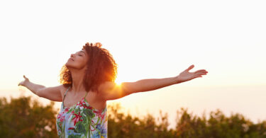 Mulher expressando liberdade ao ar com os braços para cima