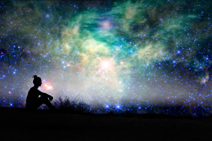Silhueta de uma mulher sentada com fundo de noite estrelada