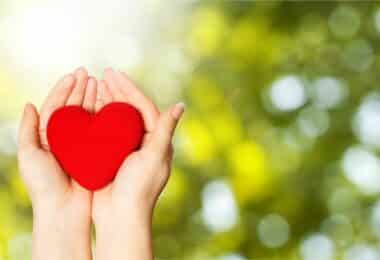 Coração vermelho na palma das mãos.