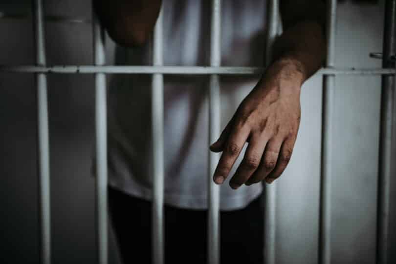 Mão de um homem preso por fora da cela