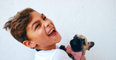 Garoto segurando filho de cachorro com gravata