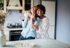 Mulher abraçando sua filha na cozinha