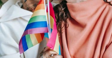 Casal de mulheres se beijando e segurando bandeira LGBT+