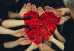 Mãos unidas pintadas de vermelho formando um coração
