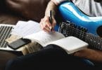 Homem com guitarra azul, escrevendo em um caderno