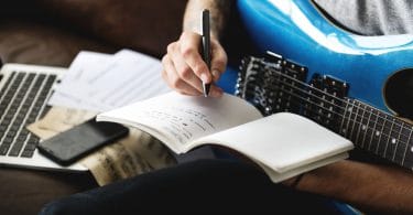 Homem com guitarra azul, escrevendo em um caderno