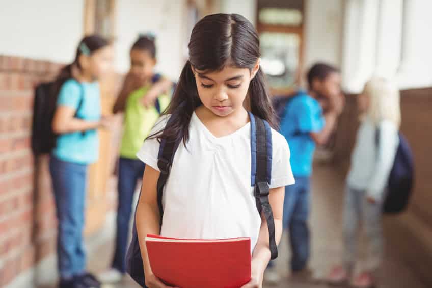 Menina andando pelo corredor da escola enquanto sofre bullying de seus colegas.