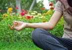 Pessoa sentada na grama, meditando, cercada por flores