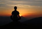 Silhueta de pessoa de costas meditando ao pôr-do-sol