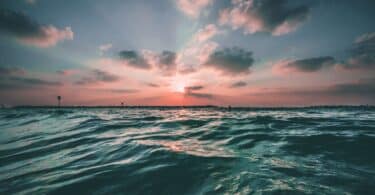 Mar visto ao pôr do Sol, com o horizonte em tons de azul e rosa.