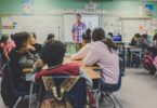 Sala de aula com alunos sentados e professor dando aula