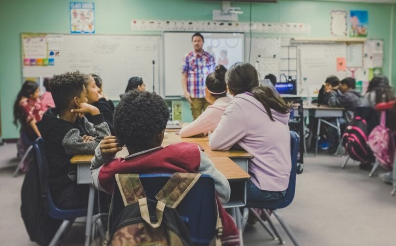 Sala de aula com alunos sentados e professor dando aula