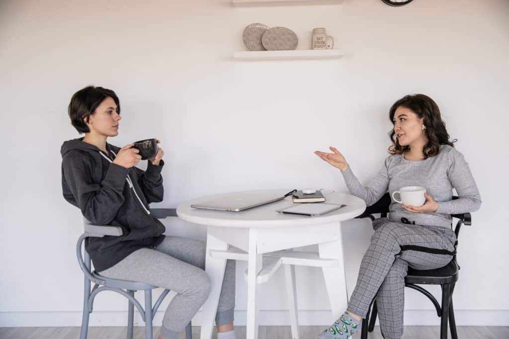 Mulheres sentadas em uma mesa segurando xícara de café