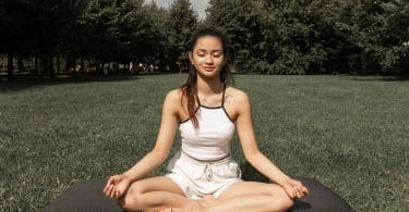 Mulher sentada em um gramado meditando