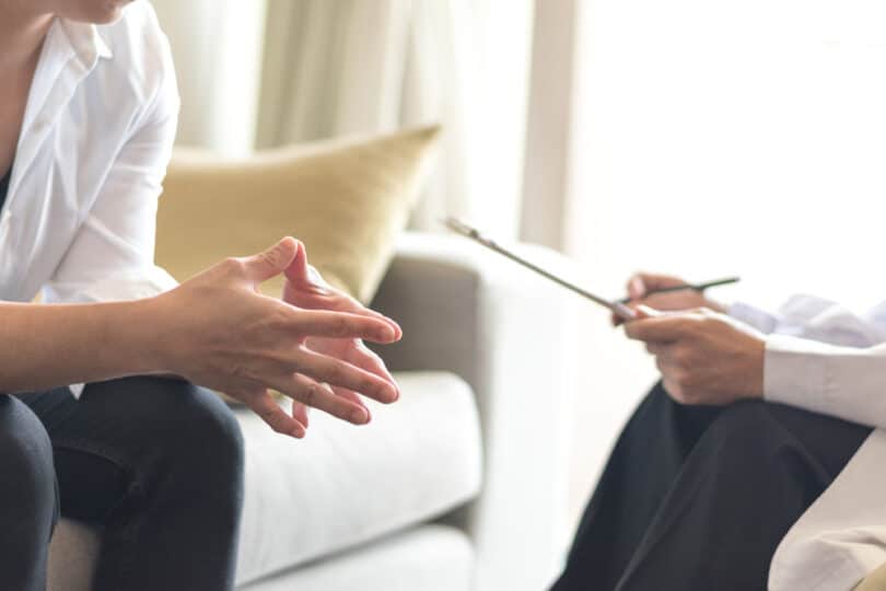 Mulher com as mãos dobradas em frente ao terapeuta