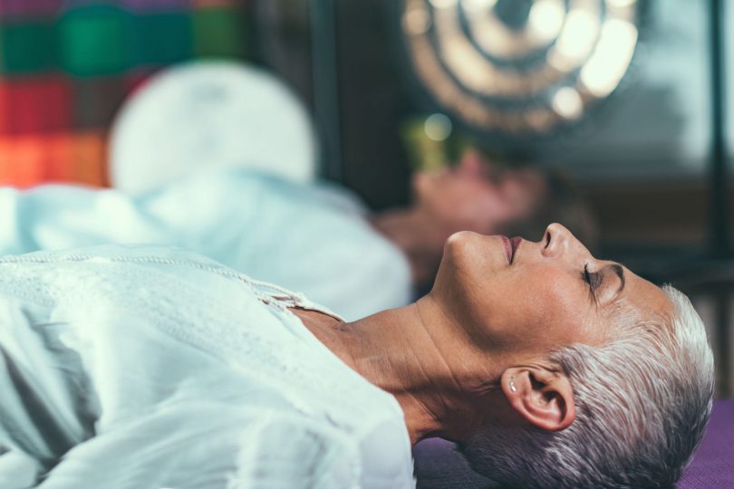 Mulher deitada de olhos fechados meditando