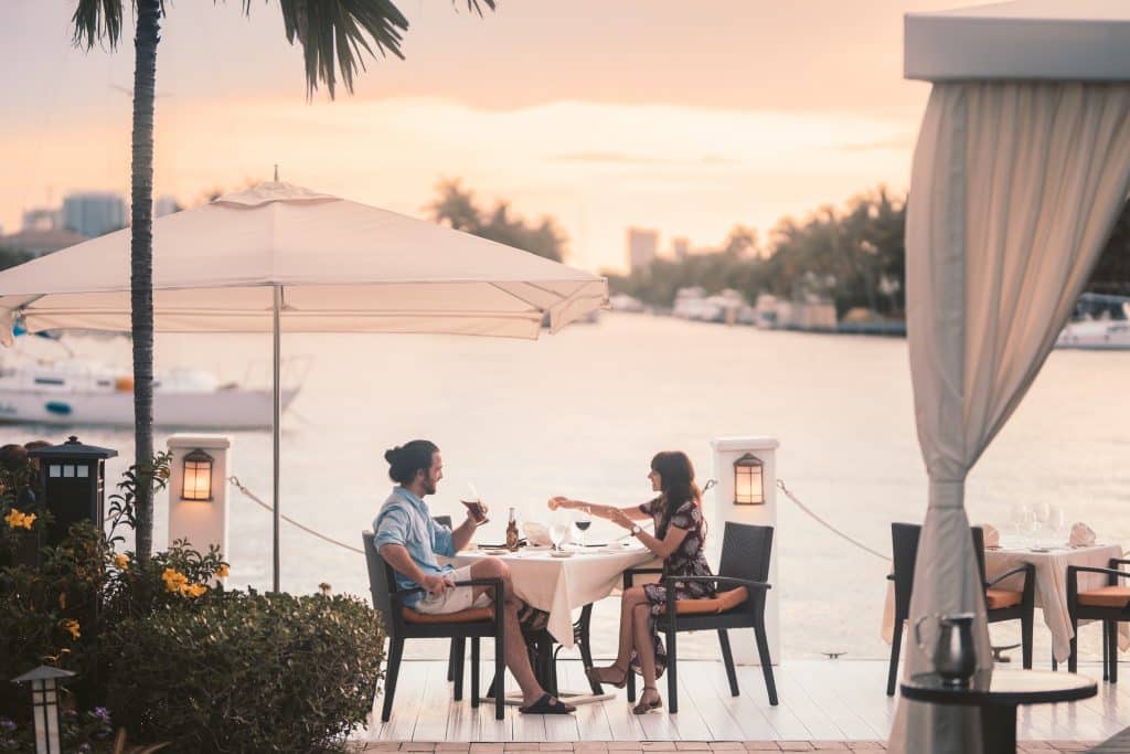 Homem e mulher sentados em um restaurante à beira mar, conversando,.