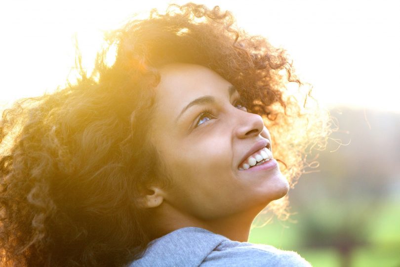 Mulher sorrindo olhando para cima.