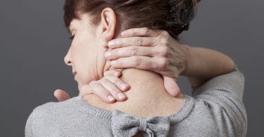 Mulher com as mãos sobre a nuca em sinal de cansaço.