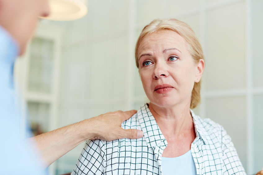 Mulher branca, aparentando meia idade, conversando com um homem, que apoia a mão no seu ombro. Aparentemente a mulher está recebendo um conselho.