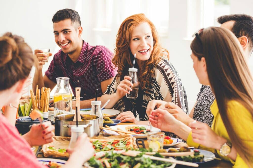 Amigos ao redor de uma mesa com vários pratos veganos.