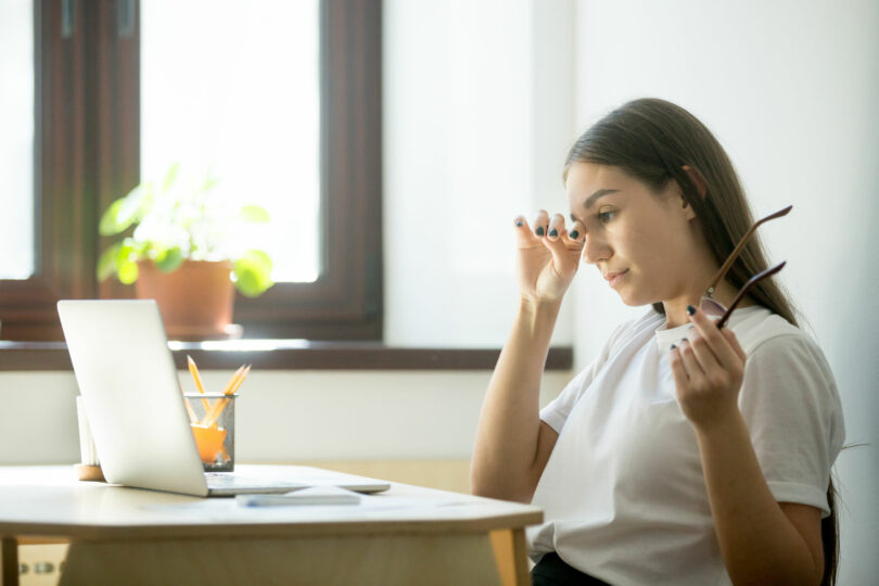 Mulher cansada em ambiente de trabalho.