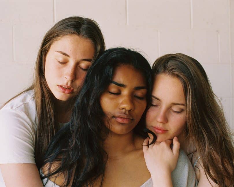 Três mulheres uma ao lado da outra de olhos fechados