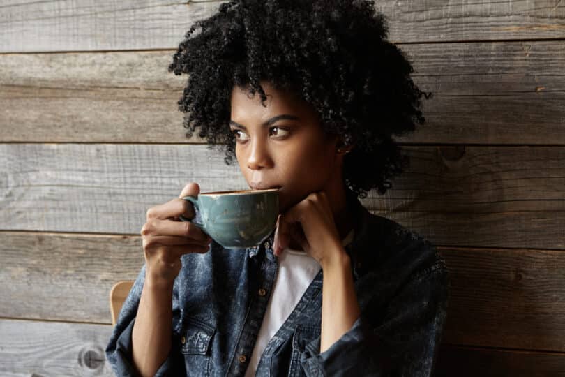 Mulher negra tomando chá numa xícara grande
