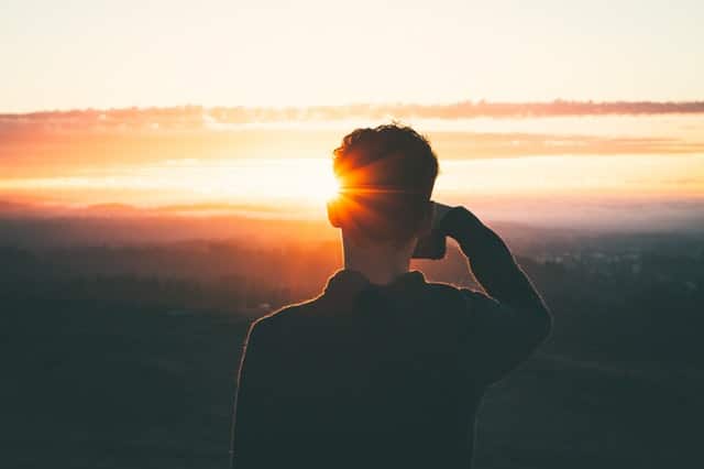 Garoto de costas com pôr-do-sol ao fundo