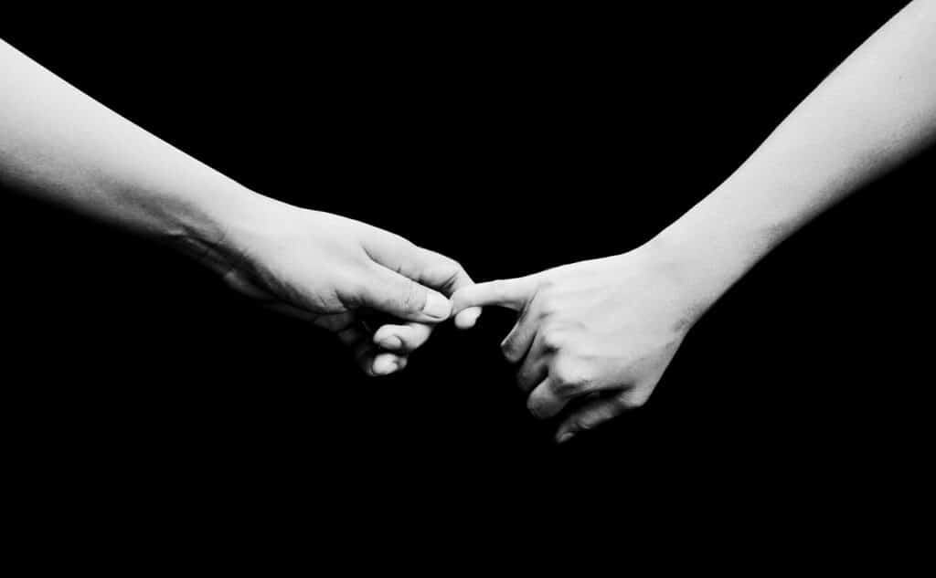 Duas pessoas segurando as mãos em preto e branco.