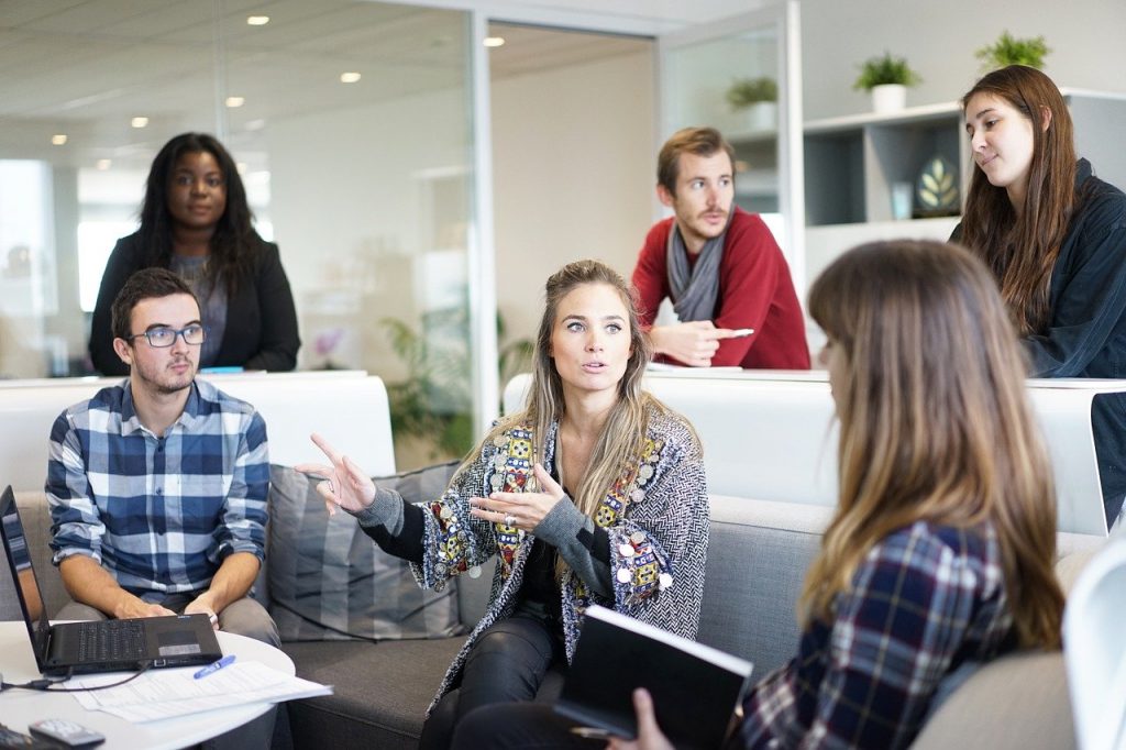 Grupo de pessoas em ambiente corporativo, conversando de maneira saudável.